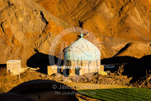 A mosque being constructed at the foot of desert mountains at sunset. Kharanagh, Yazd, Yazd Province, Islamic Republic of Iran.