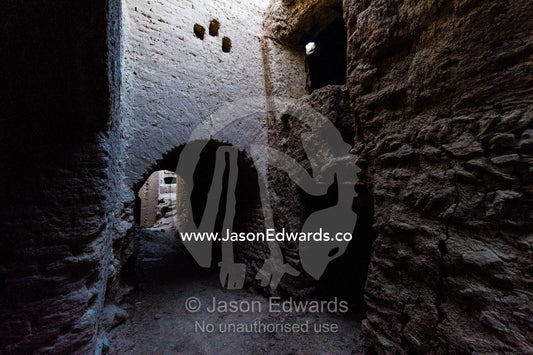 A laneway between buildings of crumbling handmade brick ruins of an ancient abandoned village in the desert. Kharanagh, Yazd, Yazd Province, Islamic Republic of Iran.