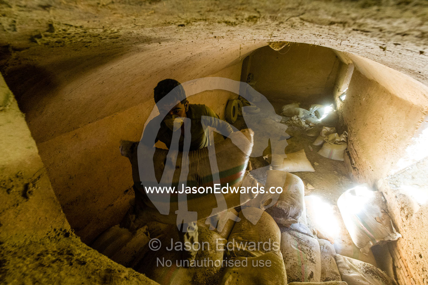 A labourer carries heavy bags of henna from an underground warehouse in a henna mill. Yazd, Yazd Province, Islamic Republic of Iran.