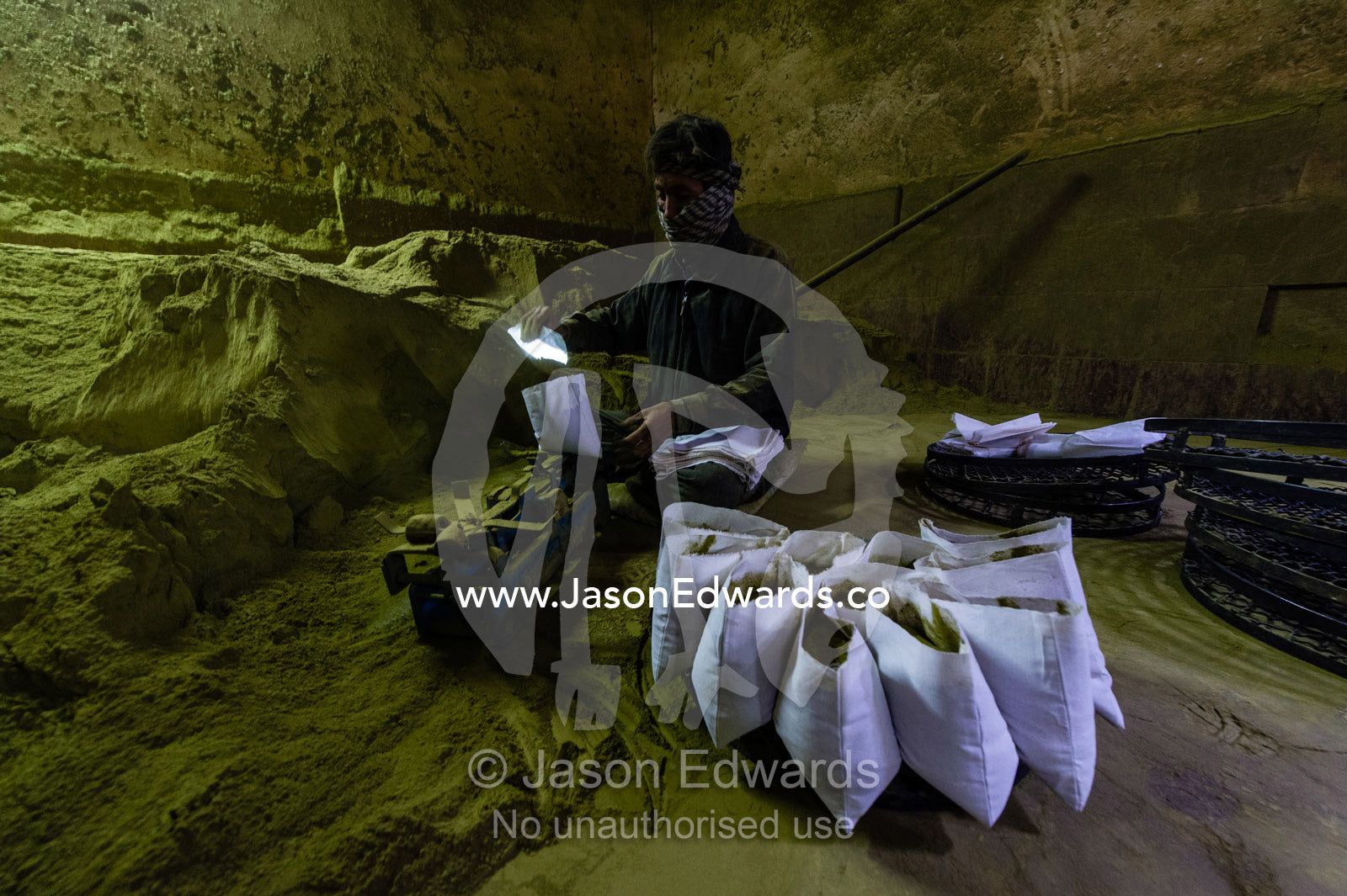 A labourer in an ancient henna mill fills bags with henna for sale. Yazd, Yazd Province, Islamic Republic of Iran.