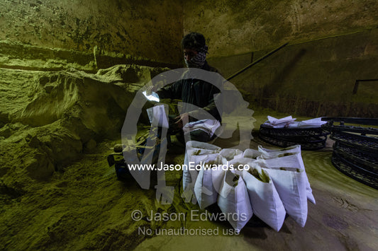 A labourer in an ancient henna mill fills bags with henna for sale. Yazd, Yazd Province, Islamic Republic of Iran.