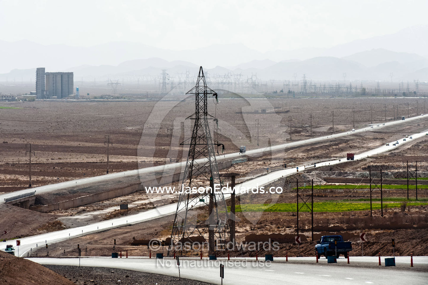 A highway and electricity towers run across the desert. Yazd, Yazd Province, Islamic Republic of Iran.