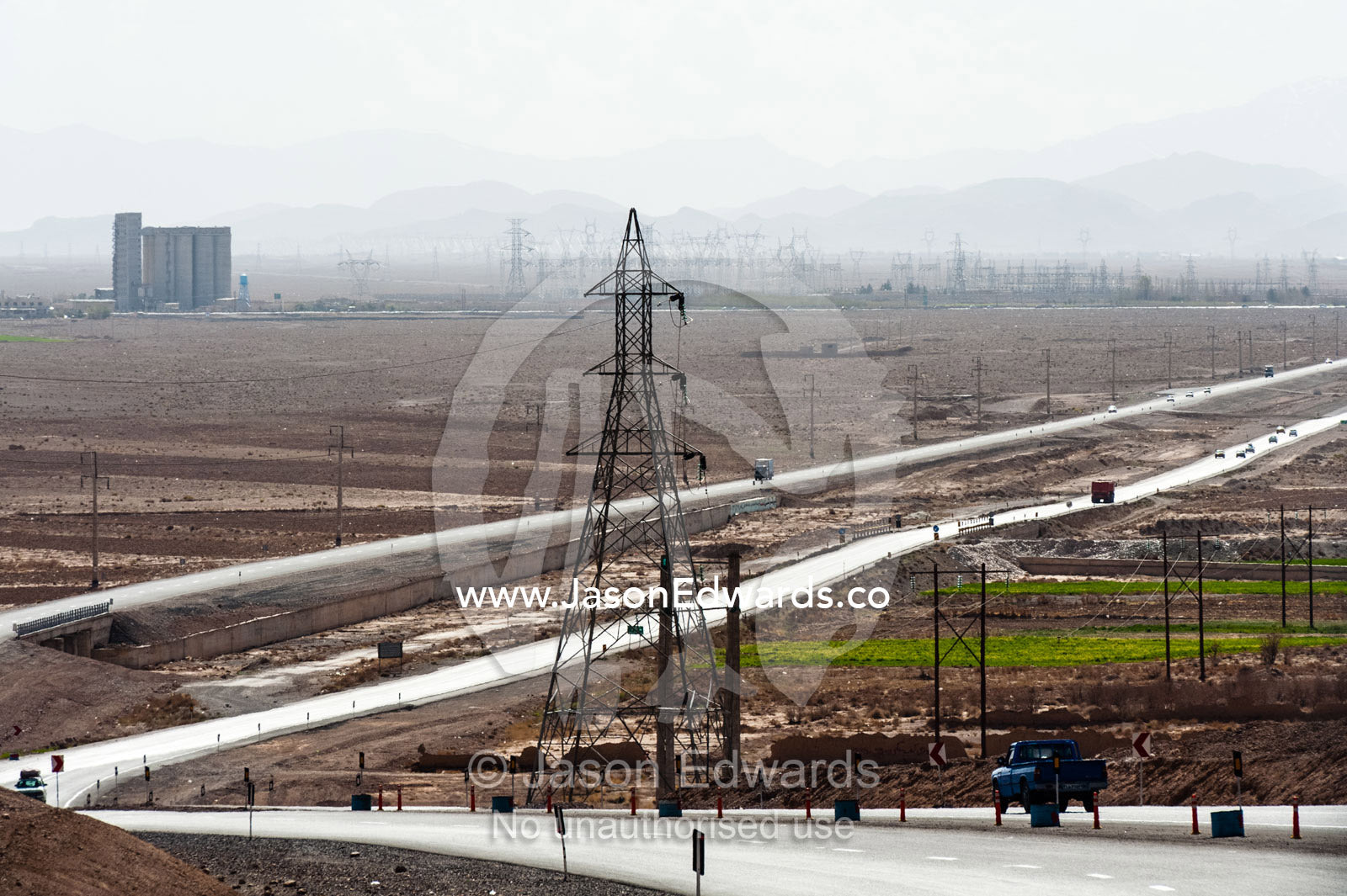 A highway and electricity towers run across the desert. Yazd, Yazd Province, Islamic Republic of Iran.
