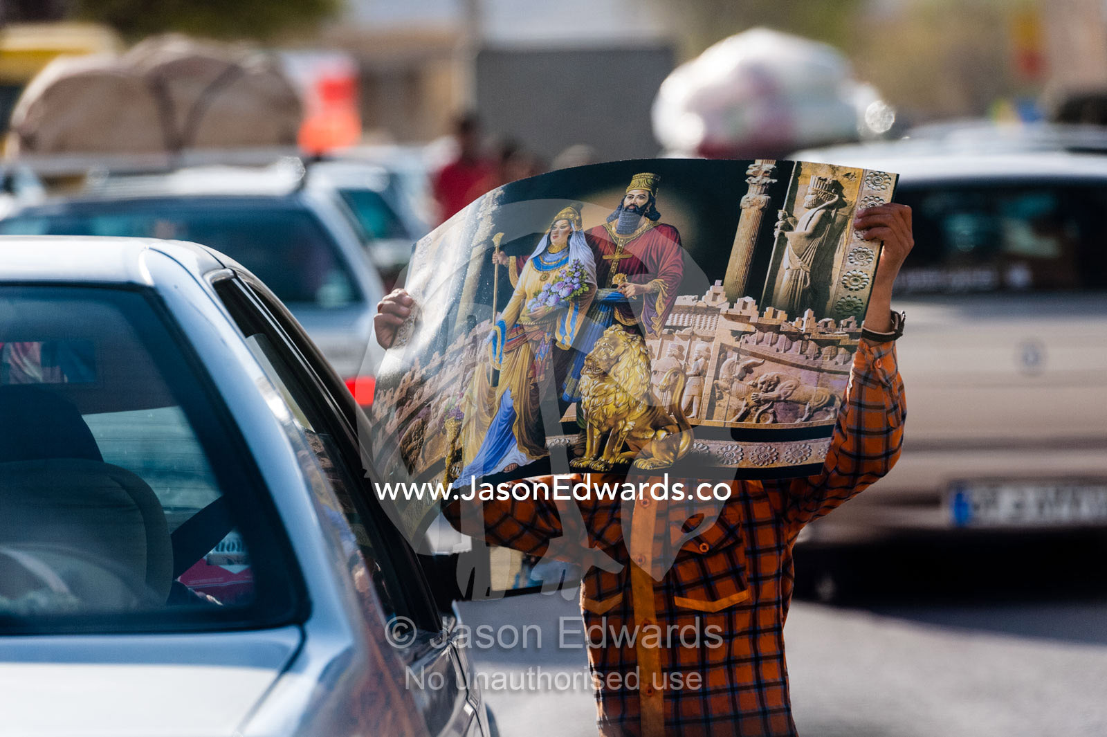 A boy attempts to sell religious posters to commuters in cars during Nowruz Iranina New Year. Fars Province, Islamic Republic of Iran.