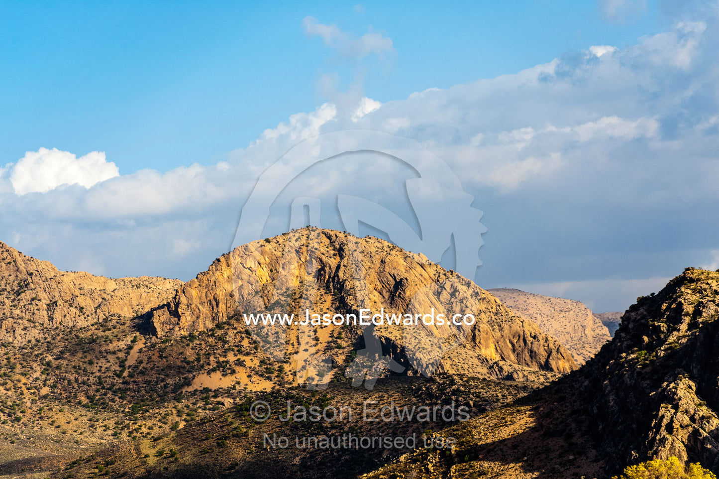 Jagged desert mountains scoured by erosion rise from a desert plain at sunset. Fars Province, Islamic Republic of Iran.
