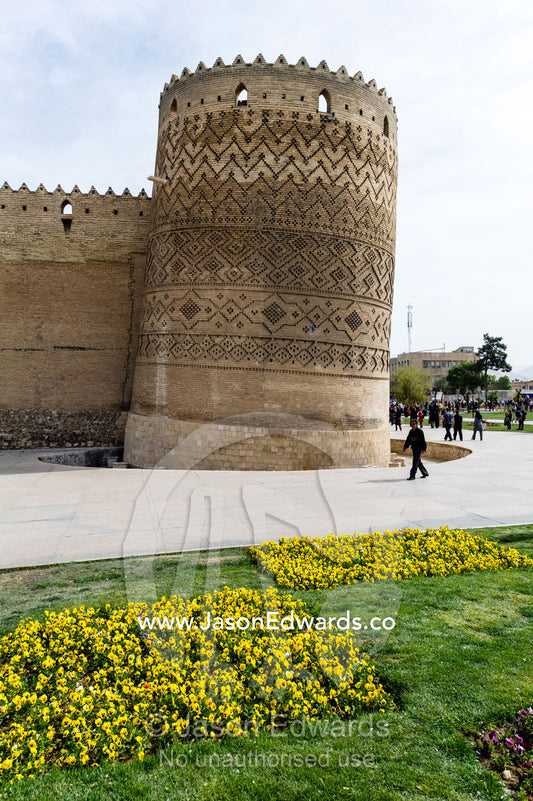 The steep walls and tower of the Karim Khan Castle surrounded by garden beds. Karim Khan Castle, Shiraz, Fars Province, Islamic Republic of Iran.