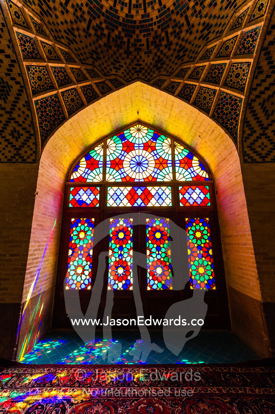 Sunlight pours through colourful stained glass windows lighting the interior of the mosque. Nasir ol Molk Mosque, Shiraz, Fars Province, Islamic Republic of Iran.