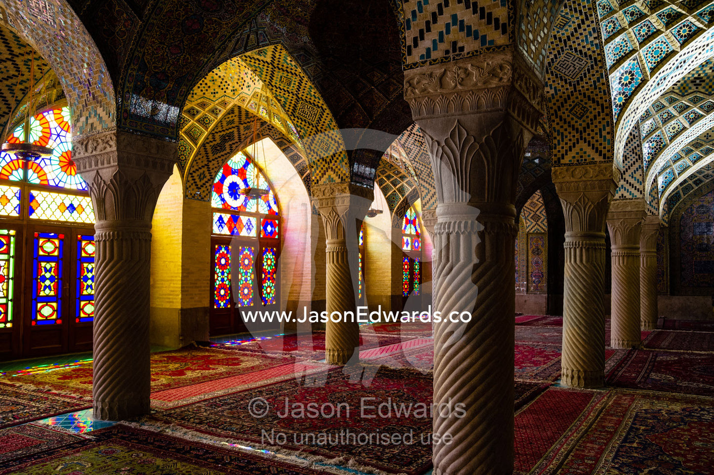 Sunlight pours through colourful stained glass windows lighting the interior of the mosque. Nasir ol Molk Mosque, Shiraz, Fars Province, Islamic Republic of Iran.