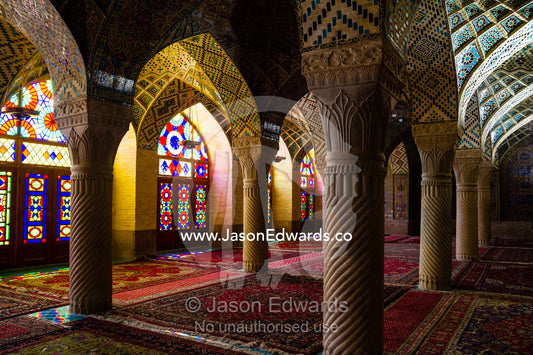 Sunlight pours through colourful stained glass windows lighting the interior of the mosque. Nasir ol Molk Mosque, Shiraz, Fars Province, Islamic Republic of Iran.
