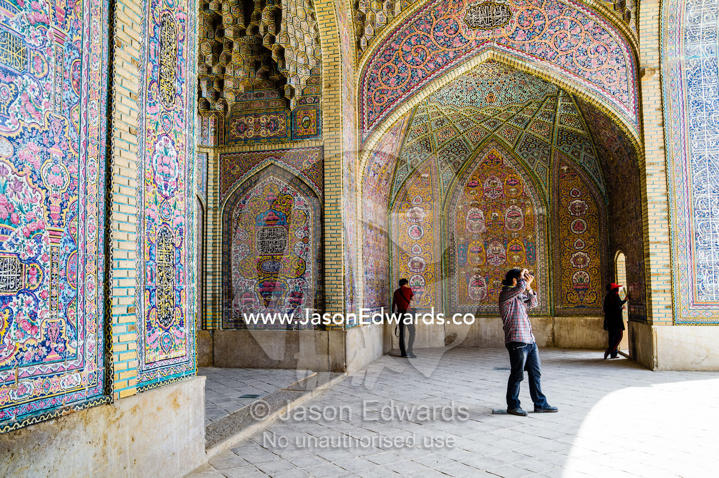 An Iranian tourist photographs the courtyard and intricate tiled muqarnas of the iwan of Nasir ol Molk Mosque. Nasir ol Molk Mosque, Shiraz, Fars Province, Islamic Republic of Iran.