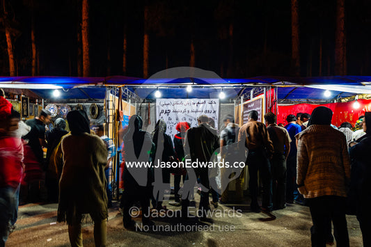 Tourists browse market stalls for souveniers of Persepolis. Persepolis, Shiraz, Fars Province, Islamic Republic of Iran.