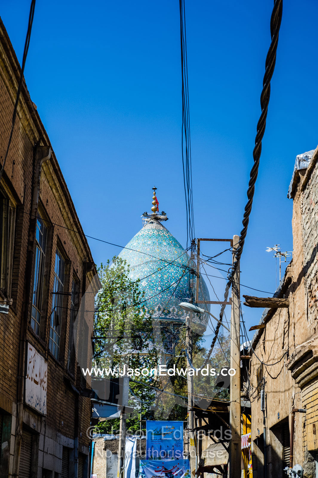 Electricity cables running above a narrow street leading to a mosque. Shiraz, Fars Province, Islamic Republic of Iran.