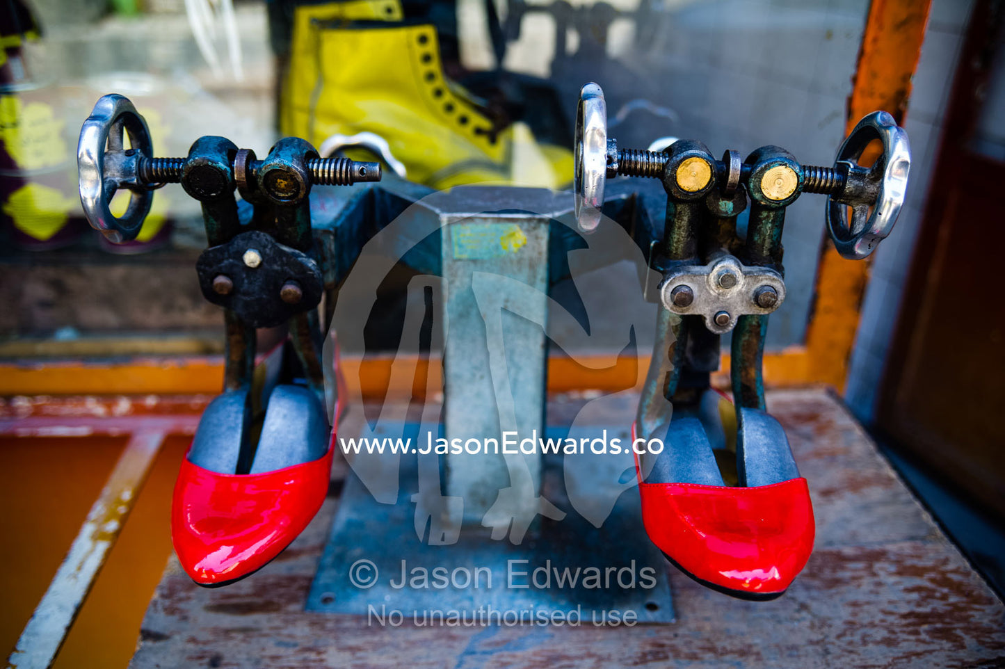 A pair of bright red womens shoes being stretch in a cobblers stall in a market. Shiraz, Fars Province, Islamic Republic of Iran.