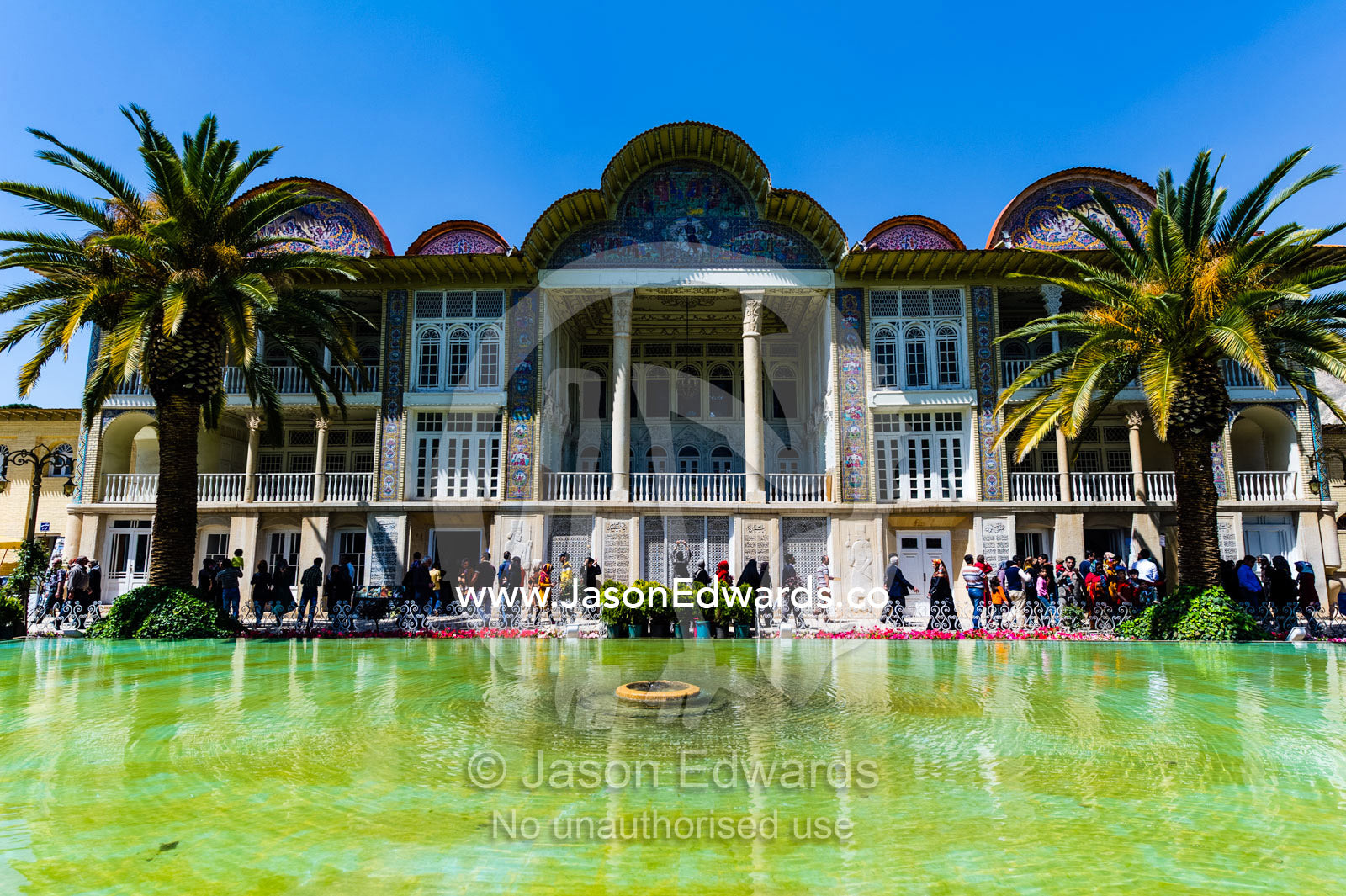 Palm trees line the facade of a large historical home overlooking a garden pond. Eram Garden, Shiraz, Fars Province, Islamic Republic of Iran.