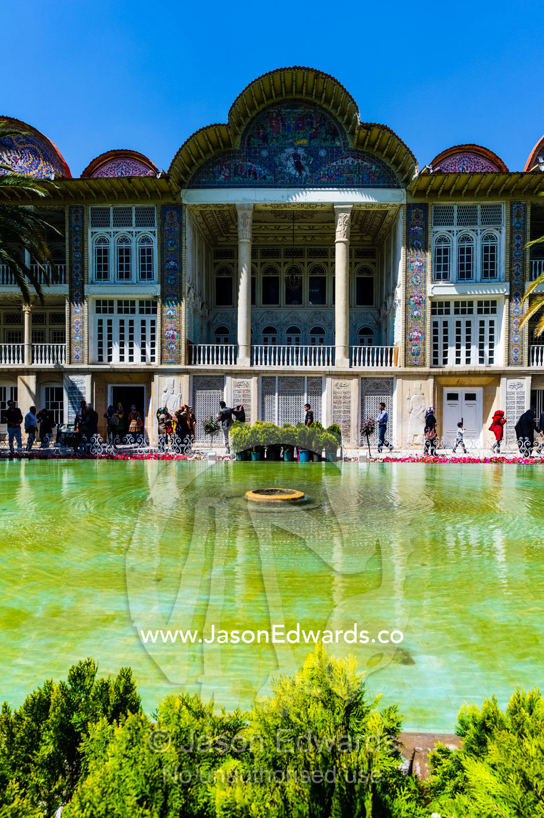 Palm trees line the facade of a large historical home overlooking a garden pond. Eram Garden, Shiraz, Fars Province, Islamic Republic of Iran.