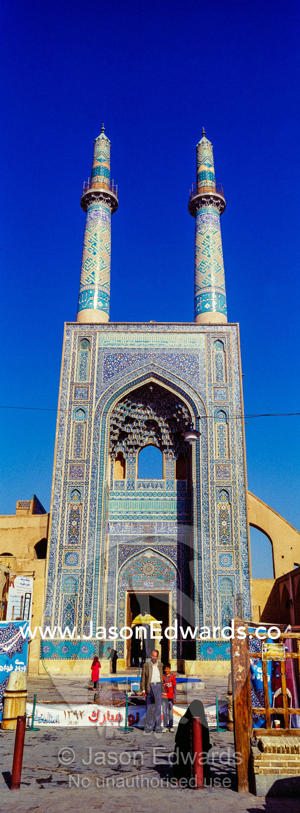 The towering blue tiled minarets above the vaulted iwan of the Jame Mosque rise into a clear blue sky. Jame Mosque of Yazd, Yazd, Yazd Province, Islamic Republic of Iran.