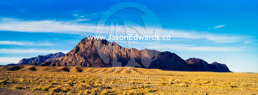 Jagged desert mountains scoured by erosion rise from a desert plain. Kharanagh, Yazd, Yazd Province, Islamic Republic of Iran.