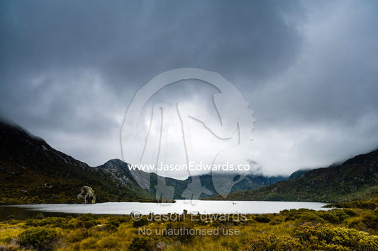 A storm descends over the forested slopes of an alpine glacial lake. Cradle Mountain, Lake St Clair National Park, Tasmania, Australia.