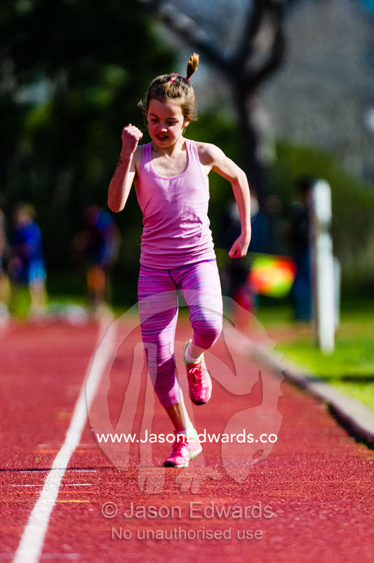 A girl runs along the track during a race at an elementary school athletics competition. Collingwood, Melbourne, Victoria, Australia.