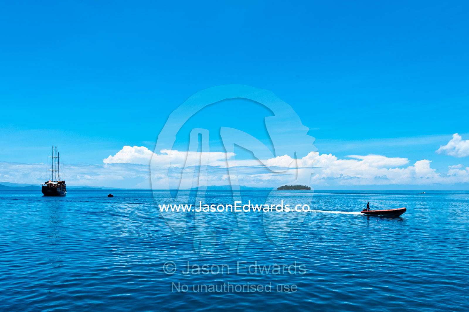 An inflatable zodiac boat speeding away for a sailing boat. Taveuni Island, Somosomo Strait, Pacific Ocean, Fiji Islands.