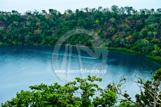 A tiny boat explores an extinct volcano caldera covered in forest. Cobia Crater, Cobia Island, Ringgold Atolls, Pacific Ocean, Fiji Islands.