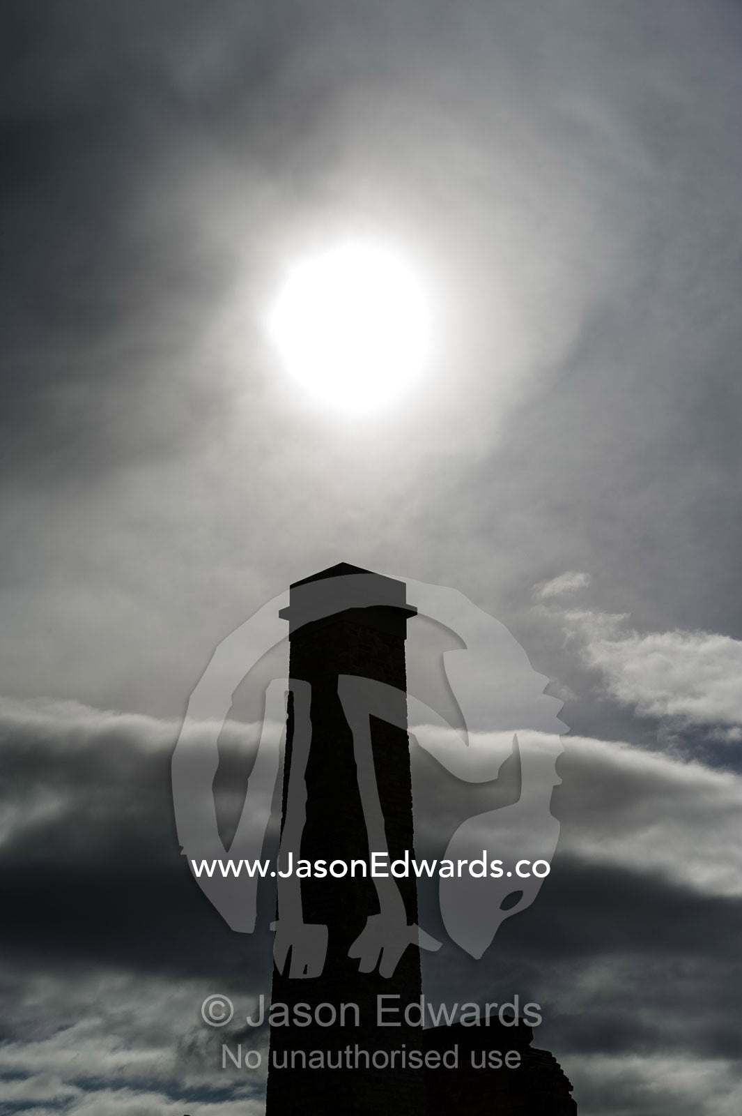 A silhouette of a towering chimney beneath a pale sun. Port Arthur Historic Site, Port Arthur, Tasmania,
Australia.