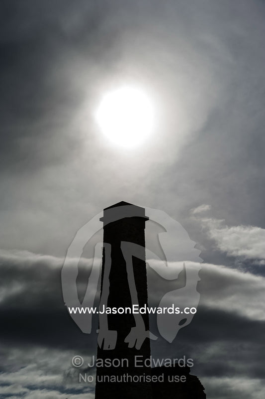 A silhouette of a towering chimney beneath a pale sun. Port Arthur Historic Site, Port Arthur, Tasmania,
Australia.