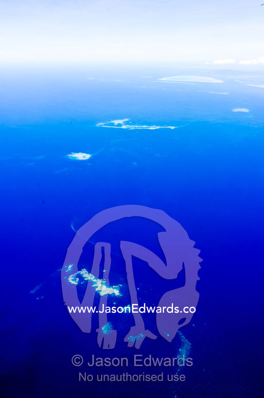 Clouds floating over a deep blue tropical ocean with isolated sandbars. Taveuni Island, Somosomo Strait, Pacific Ocean, Fiji Islands.
