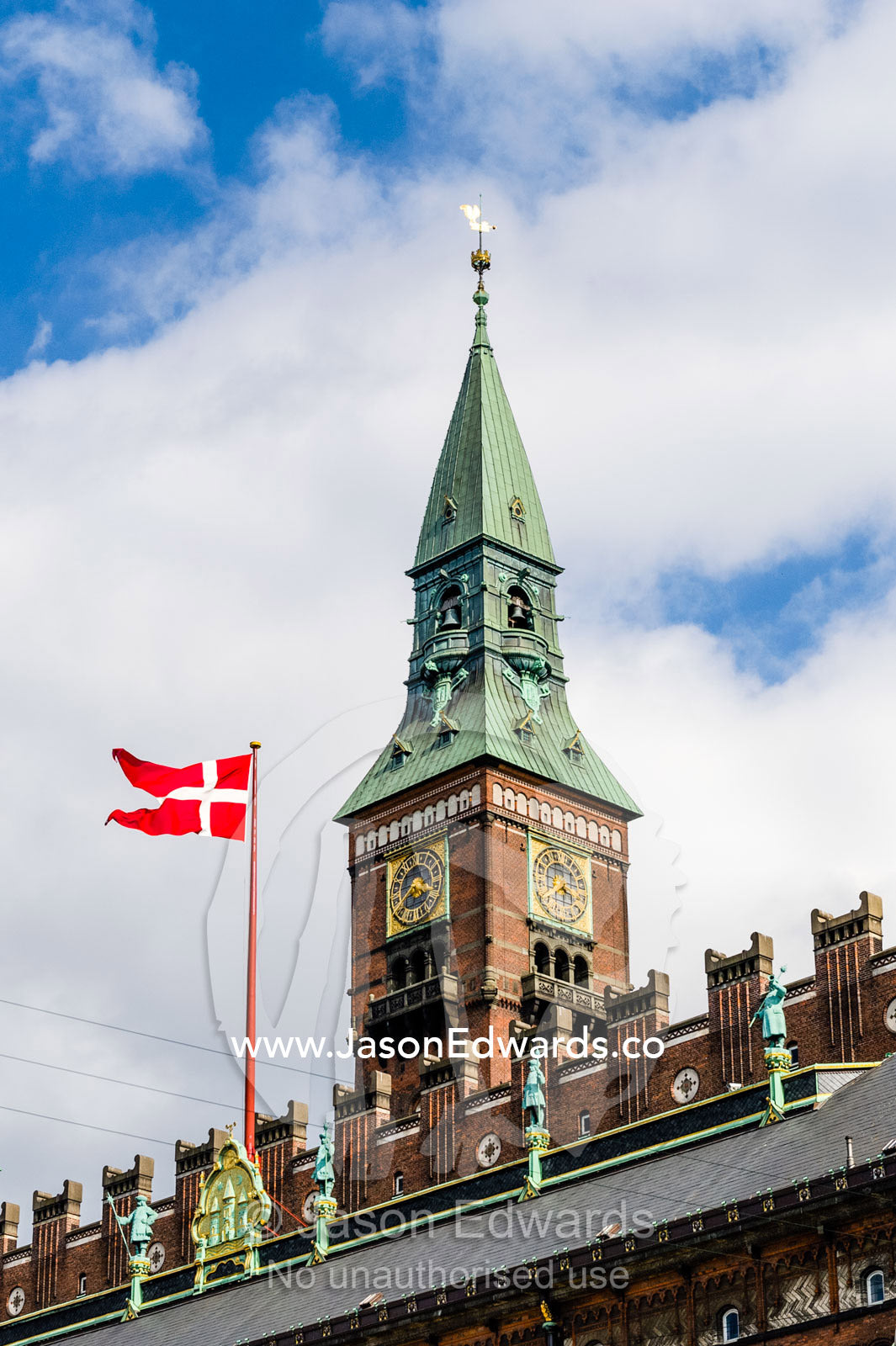 The clock tower and Danish flag flying over City Hall in Copenhagen. Copenhagen, Denmark.