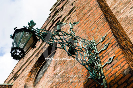An ornate steel lantern bracket on the imposing brick and glass facade of the Church of the Holy Spirit. Church of the Holy Spirit, Copenhagen, Denmark.