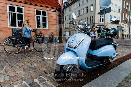 A motorbike parked on a cobblestone street by a canal. Copenhagen, Denmark.