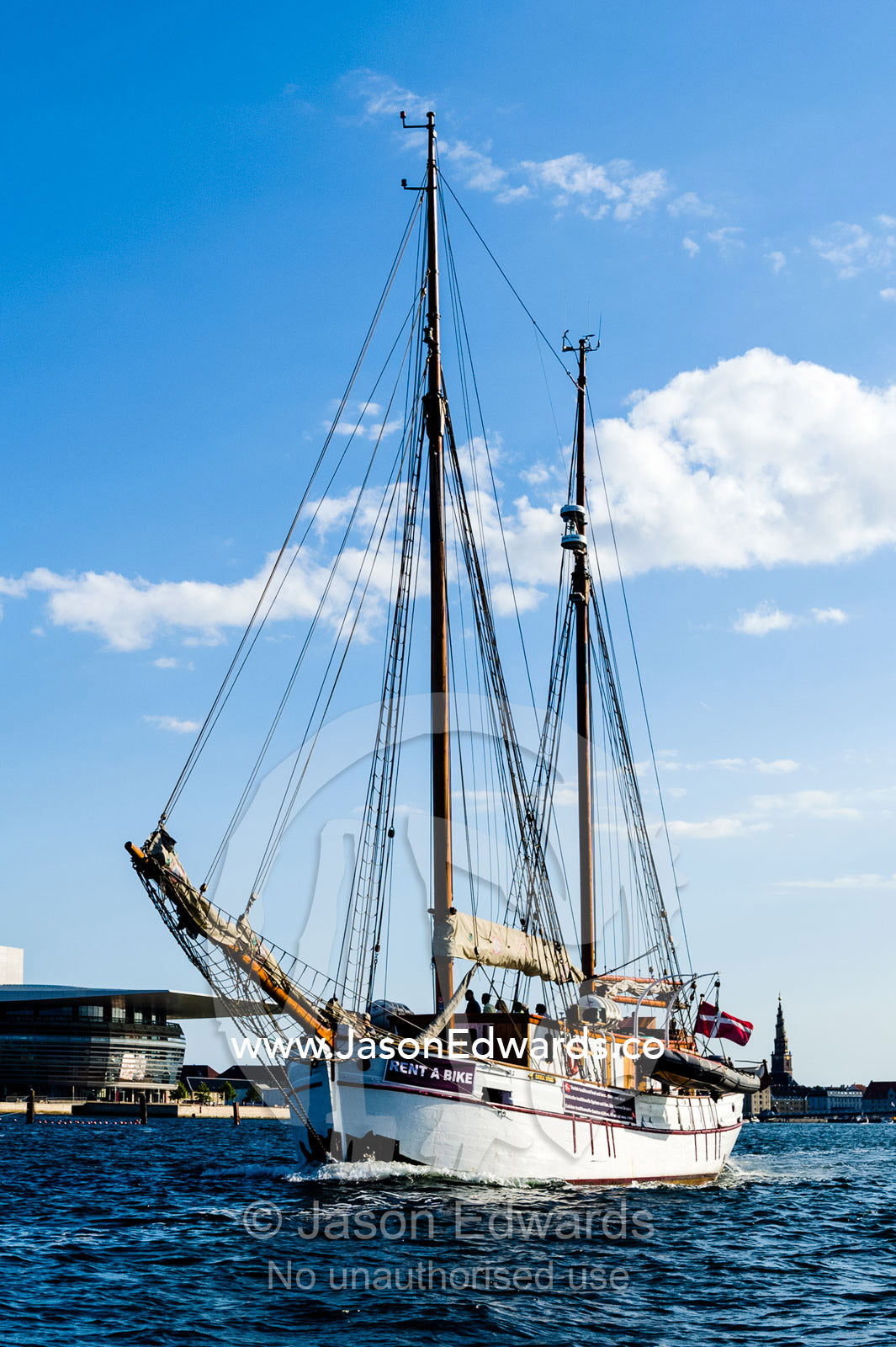 An antique timber yacht motors along a canal in Copenhagen. Holmen, Copenhagen, Denmark.