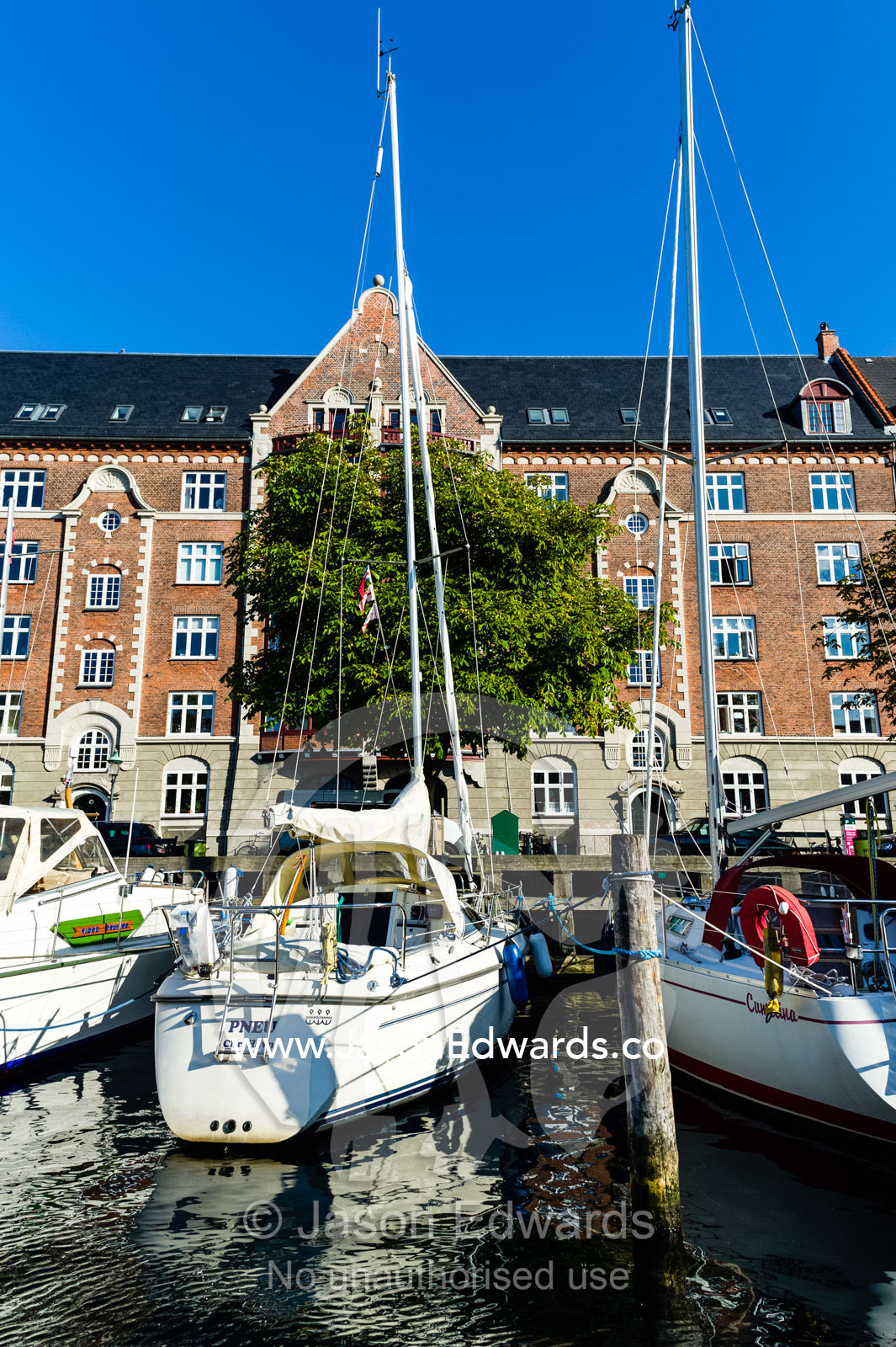 A yacht moored beside apartments in a canal in Copenhagen. Copenhagen, Denmark.