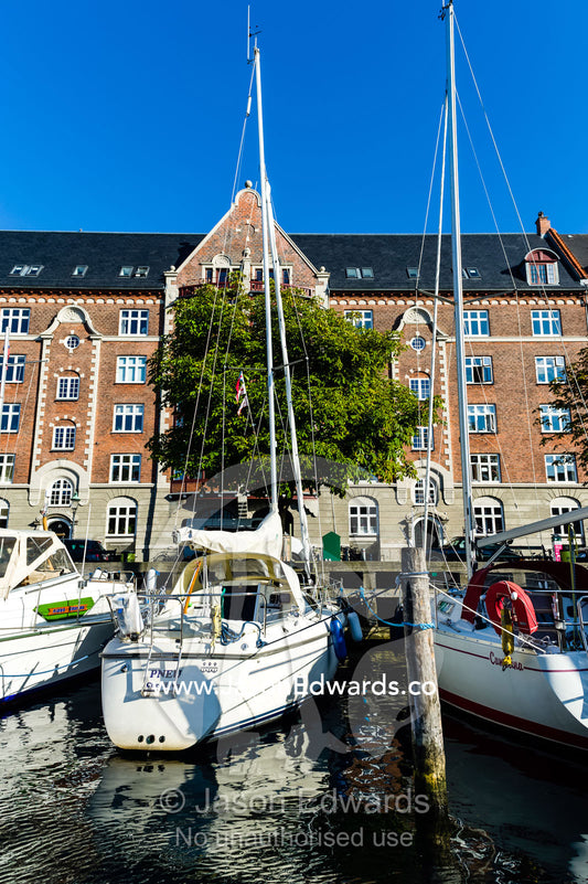 A yacht moored beside apartments in a canal in Copenhagen. Copenhagen, Denmark.