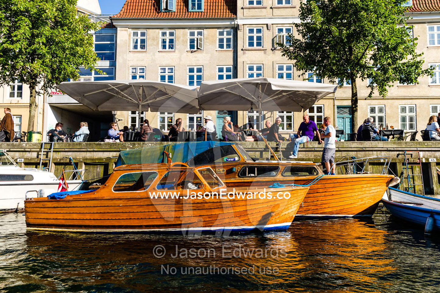 Antique timber motorboats  moored beside apartments in a canal in Copenhagen. Copenhagen, Denmark.