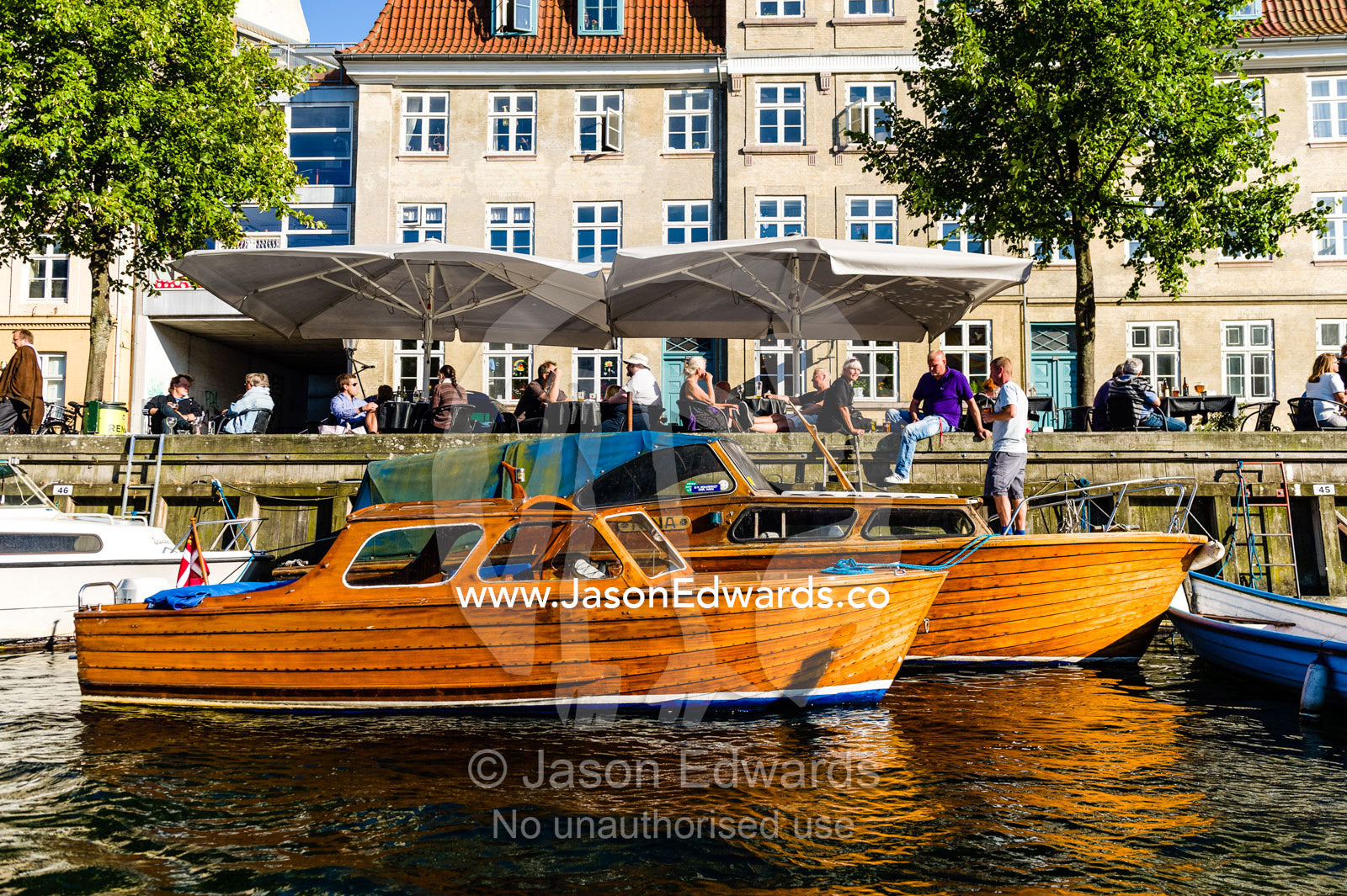 Antique timber motorboats  moored beside apartments in a canal in Copenhagen. Copenhagen, Denmark.