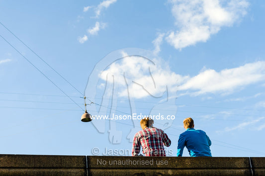 Friends sitting on a bridge above a canal in Copenhagen. Copenhagen, Denmark.