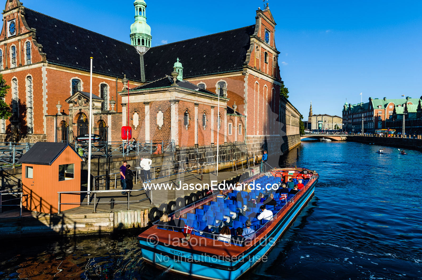 A canal boat with tourists moors beside the Holmen Church in Copenhagen. Holmen Church, Copenhagen, Denmark.