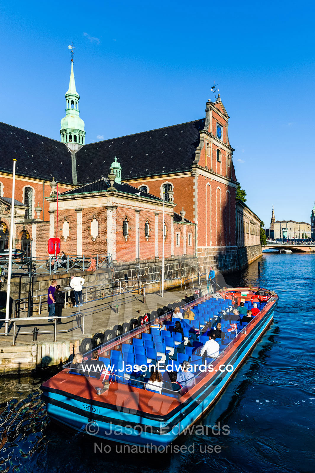 A canal boat with tourists moors beside the Holmen Church in Copenhagen. Holmen Church, Copenhagen, Denmark.