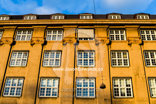 Sunset falls across the windows and facade of a heritage building in Copenhagen. Copenhagen, Denmark.
