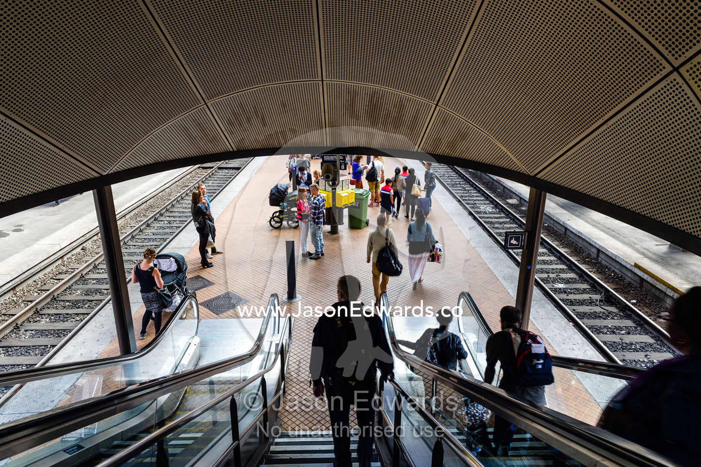 Commuters descending escalators to a train platform. Copenhagen Central Train Station, Copenhagen, Denmark.