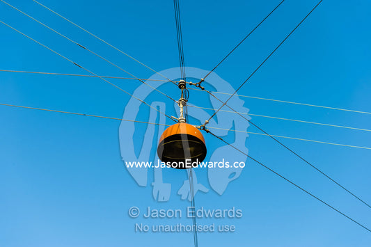 A rusting light shade suspended over a road intersection on cables. Town Square, Copenhagen, Denmark.