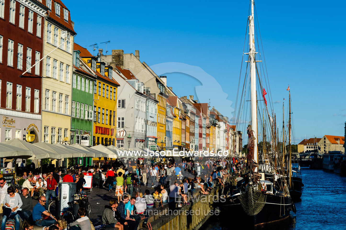 Colorful buildings, restaurants and diners along a canal in summer. Nyhavn Canal, Copenhagen, Hovedstaden Region, Denmark.