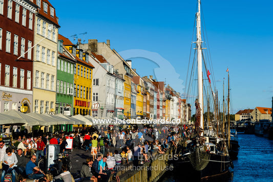 Colorful buildings, restaurants and diners along a canal in summer. Nyhavn Canal, Copenhagen, Hovedstaden Region, Denmark.