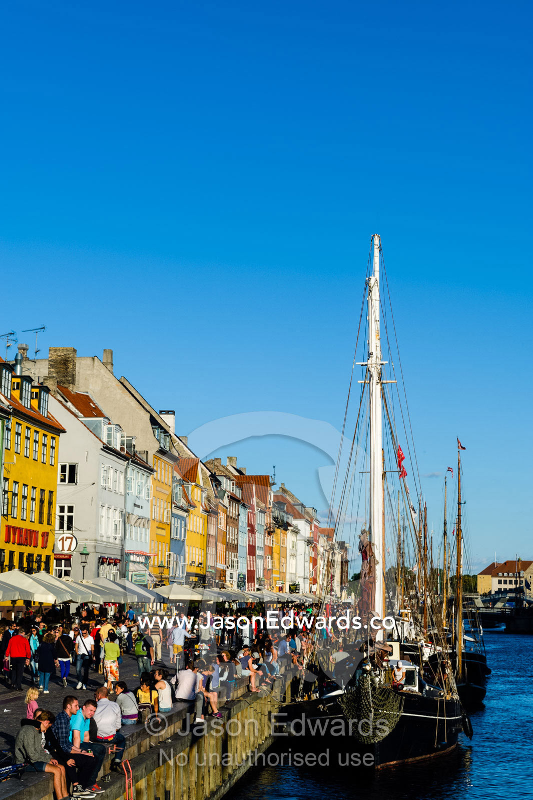 Colorful buildings, restaurants and diners along a canal in summer. Nyhavn Canal, Copenhagen, Hovedstaden Region, Denmark.