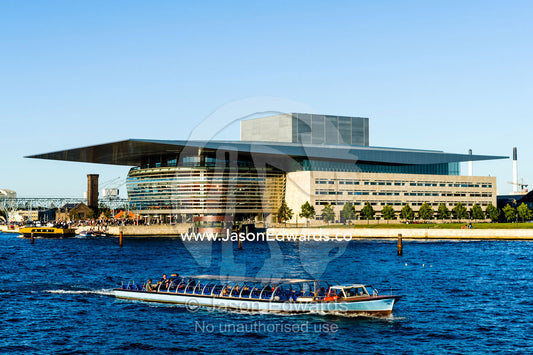A canal boat carries tourists past the Copenhagen Opera House on a tour. Copenhagen Opera House, Holmen, Copenhagen, Denmark.
