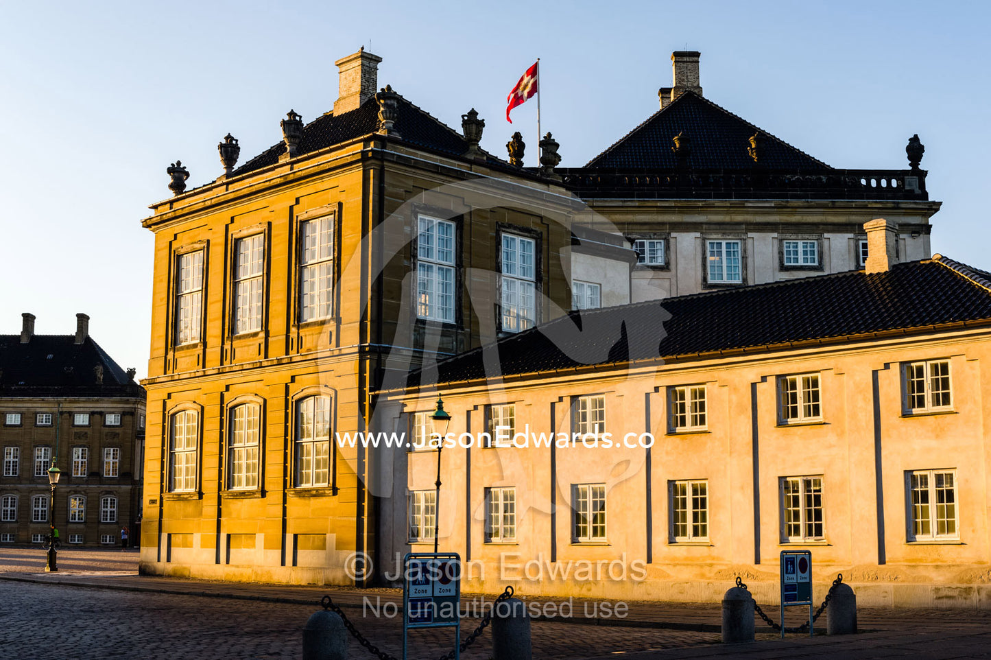 Sunset falls across the facade of the Royal Palace and it's cobblestone courtyard. Amalienborg Palace, Copenhagen, Denmark.