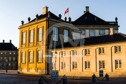 Sunset falls across the facade of the Royal Palace and it's cobblestone courtyard. Amalienborg Palace, Copenhagen, Denmark.