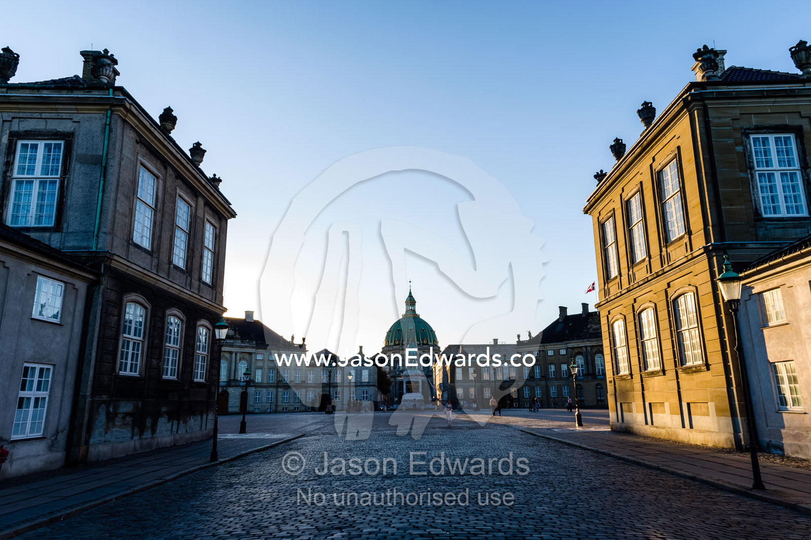 Sunset falls across the facade of the Royal Palace and it's cobblestone courtyard. Amalienborg Palace, Copenhagen, Denmark.
