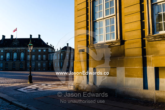 Sunset falls across the facade of the Royal Palace and it's cobblestone courtyard. Amalienborg Palace, Copenhagen, Denmark.